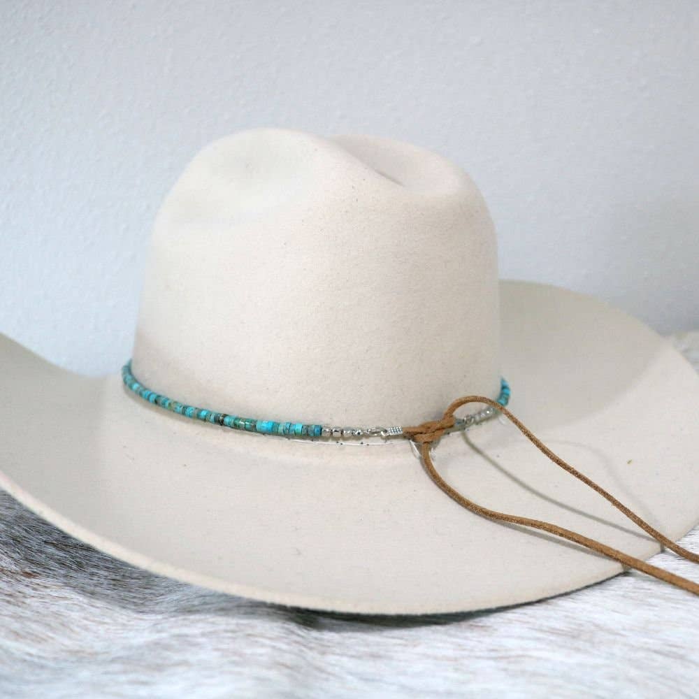 Beige cowboy hat with turquoise beads and leather strap.