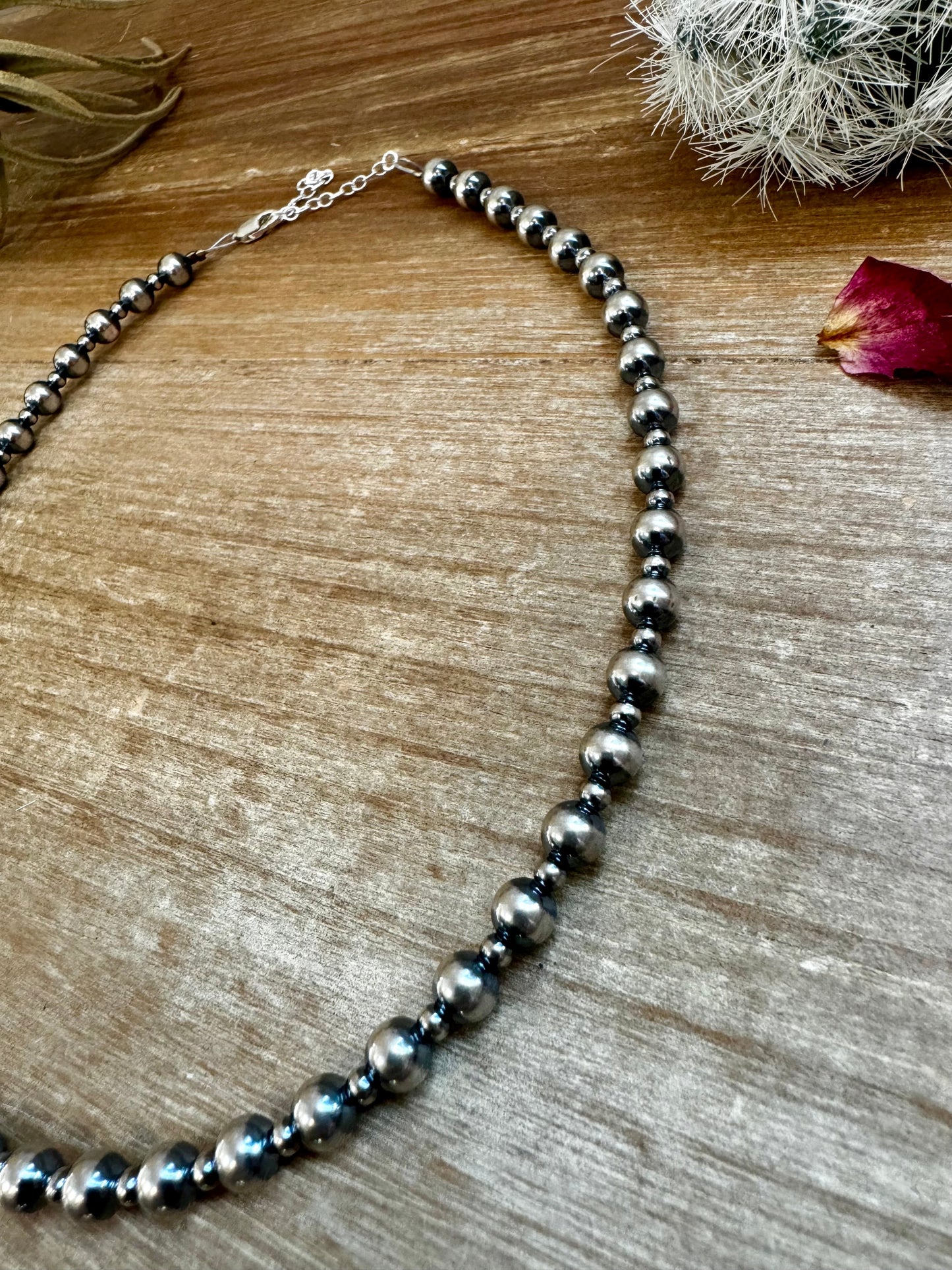 Silver bead necklace on wood, 0BD580A2-20BD