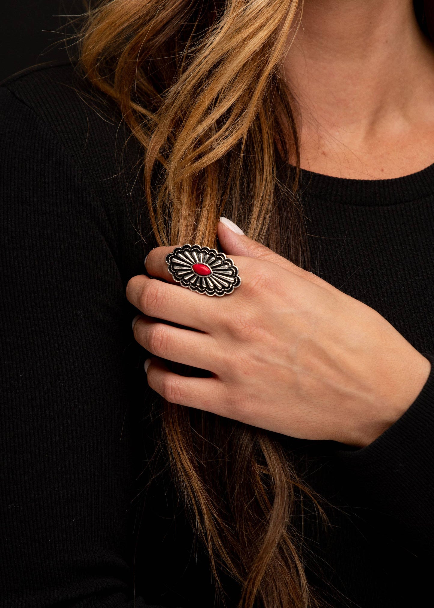 Woman's hand wearing a silver ring with a red stone.
