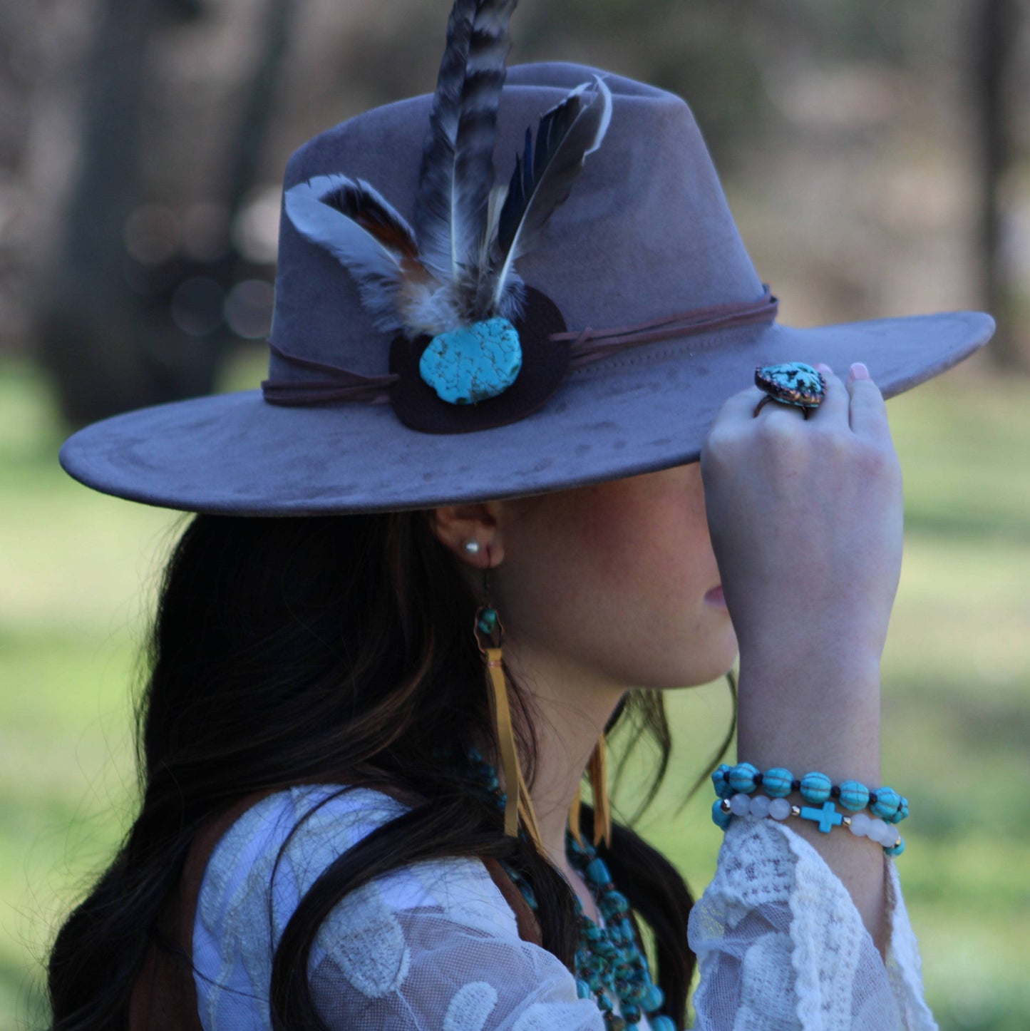 Woman wearing hat with feather and turquoise.