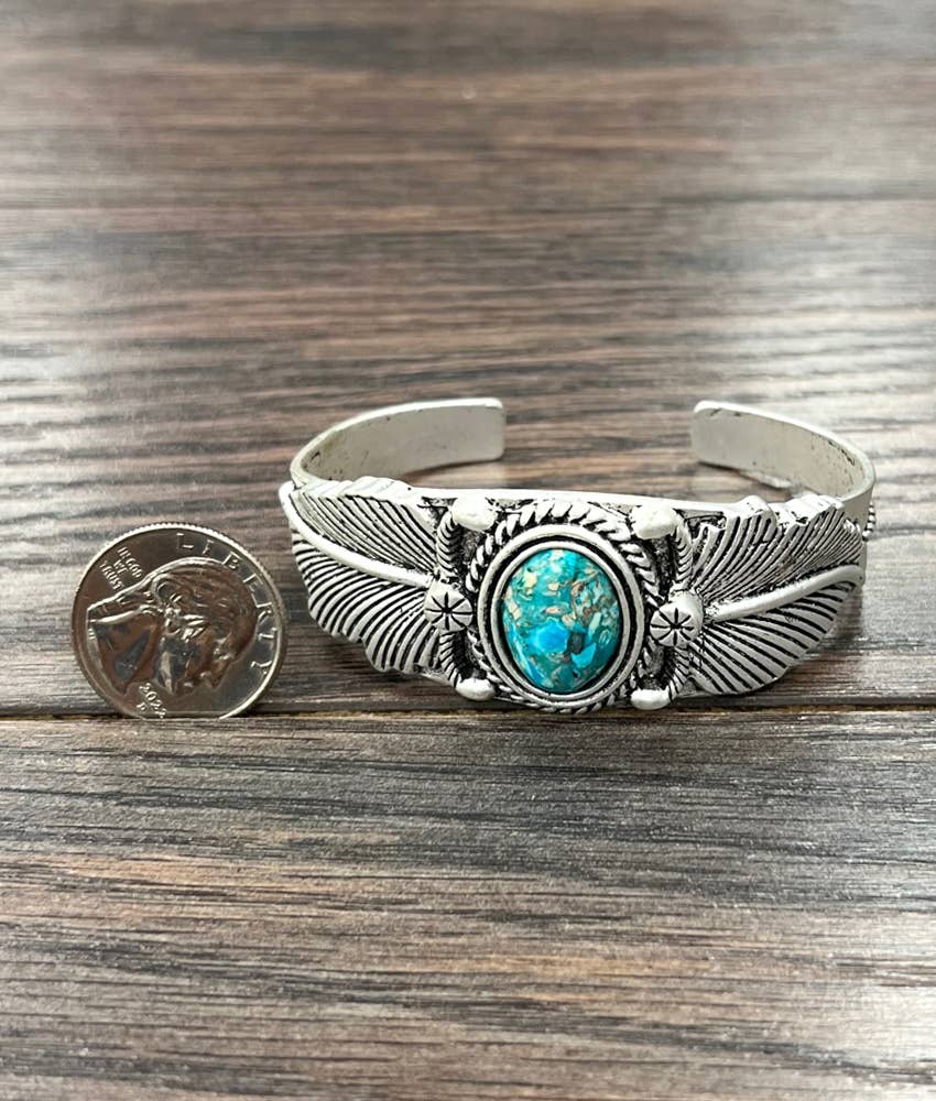 Silver cuff bracelet with turquoise stone and coin.