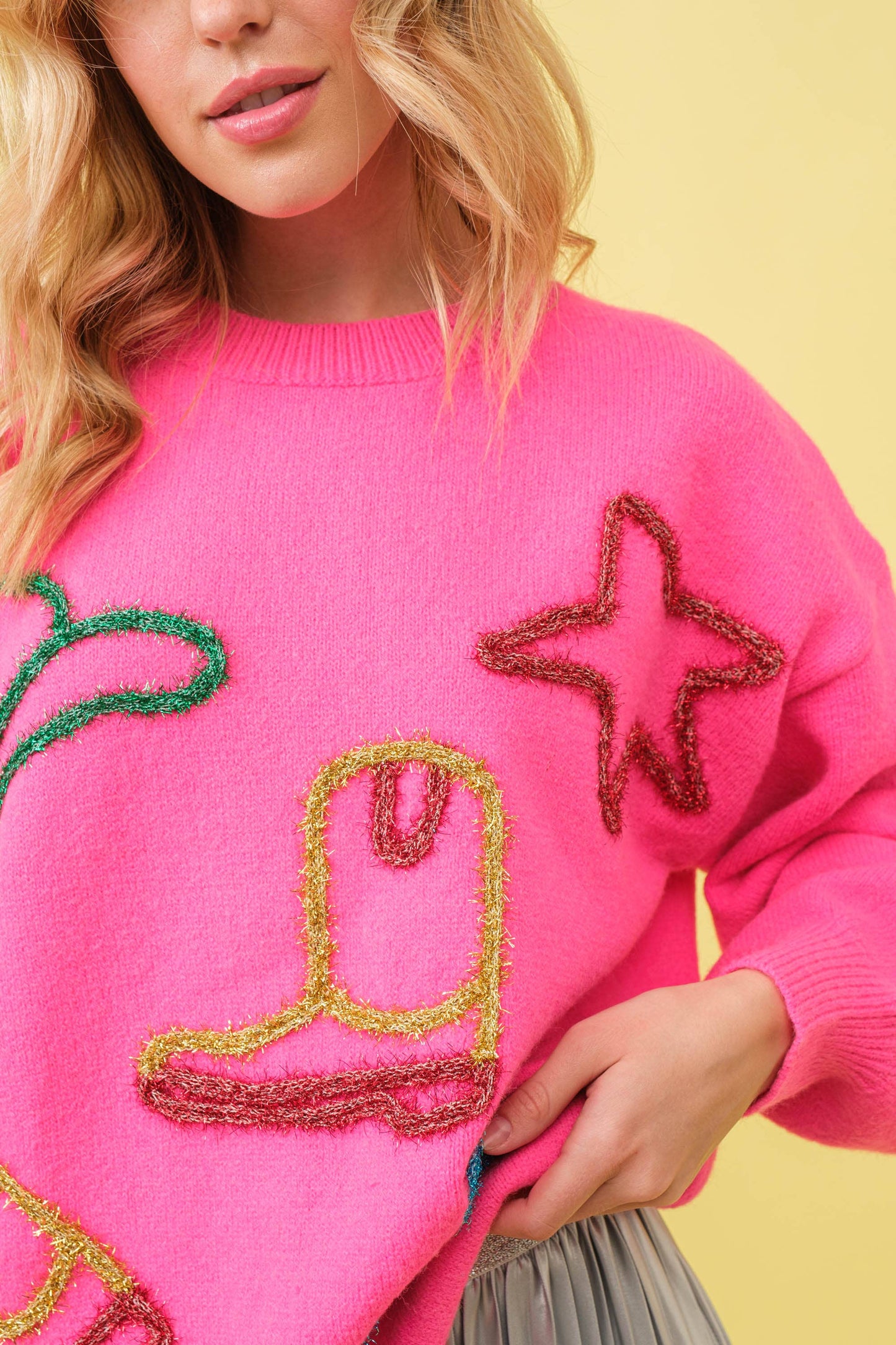 Woman in a pink sweater with embroidered star and boot.