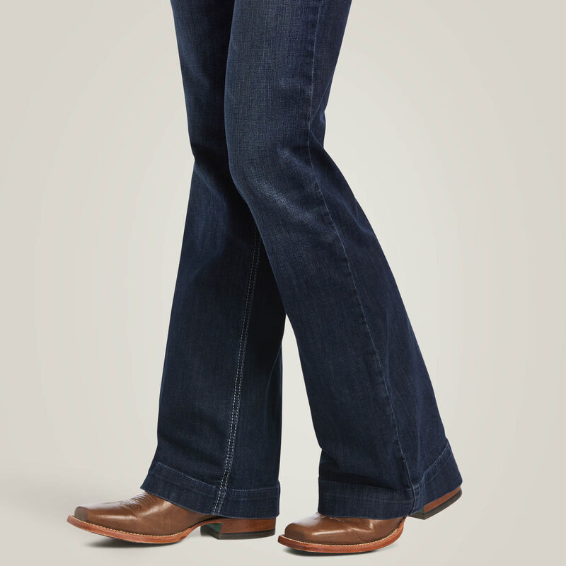 Person wearing dark blue flared jeans and brown cowboy boots.