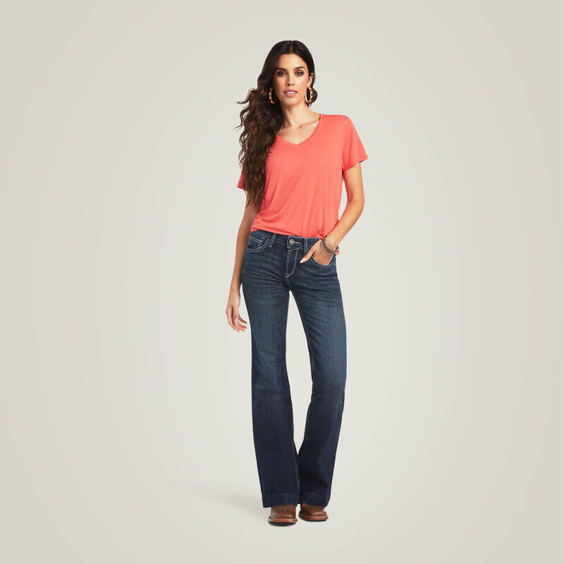 Woman wearing a coral shirt and dark blue jeans.