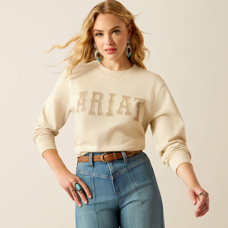 Woman wearing Ariat sweatshirt and jeans.