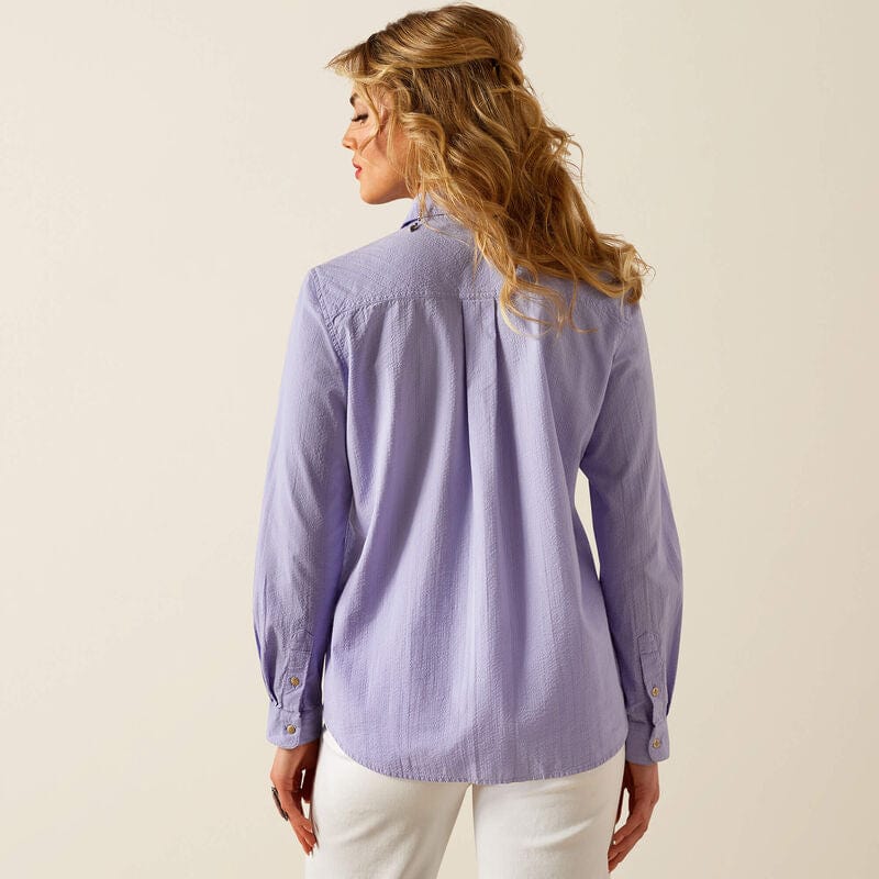 Woman wearing a purple striped shirt and white pants.