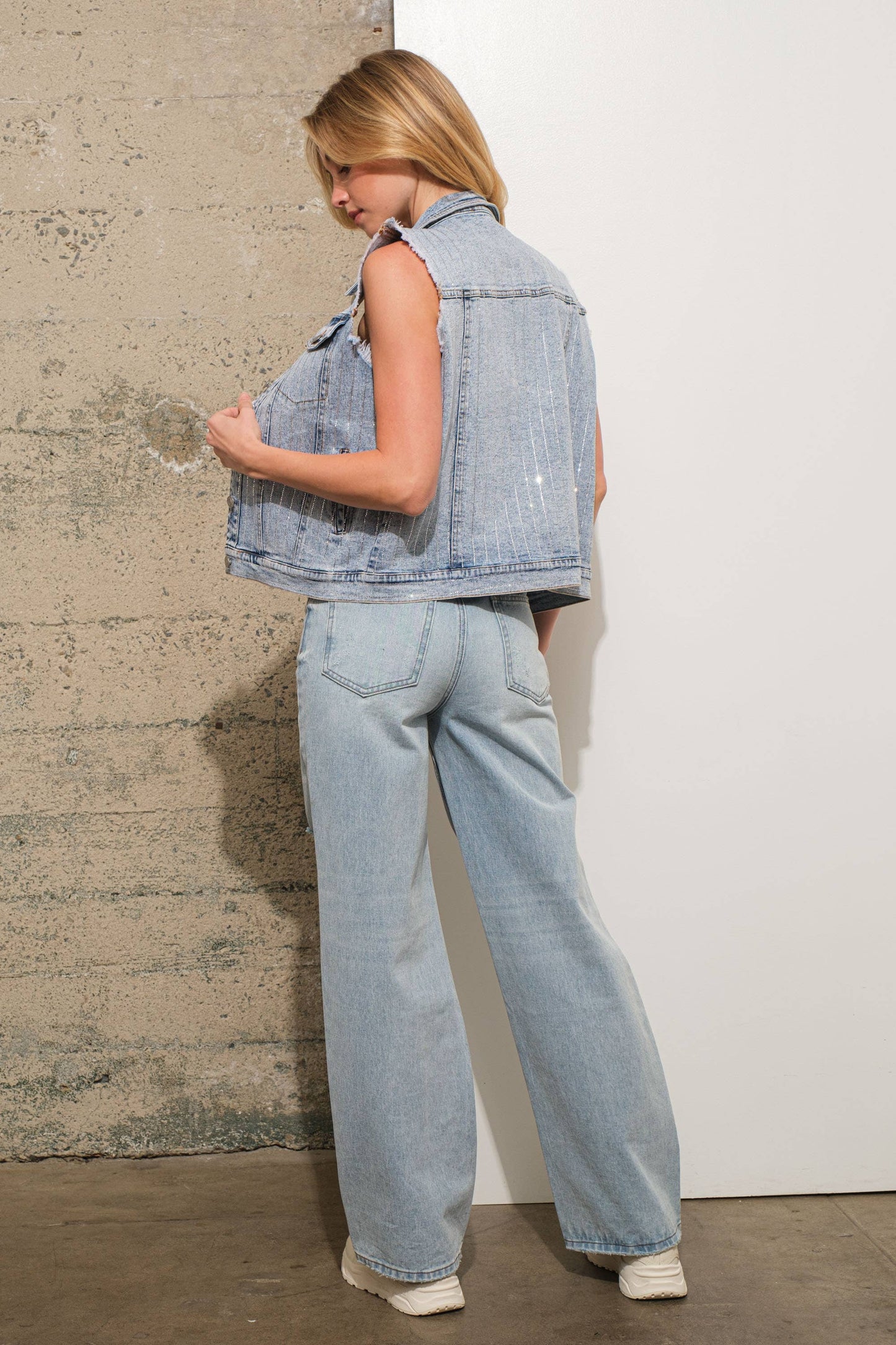 Woman in denim vest and jeans.