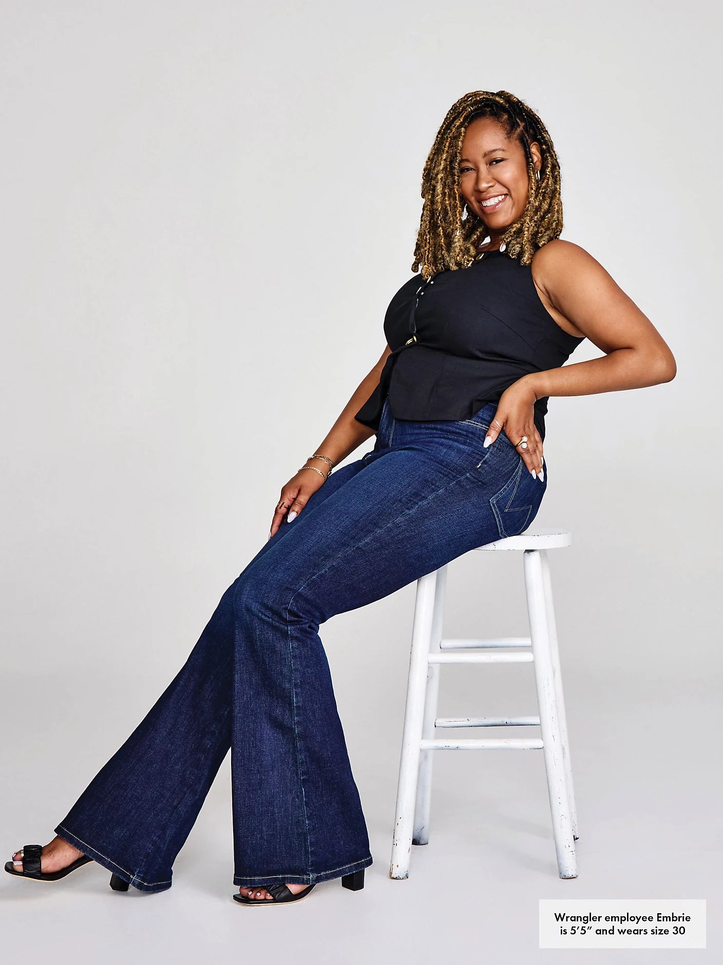 Woman in jeans sitting on a stool.