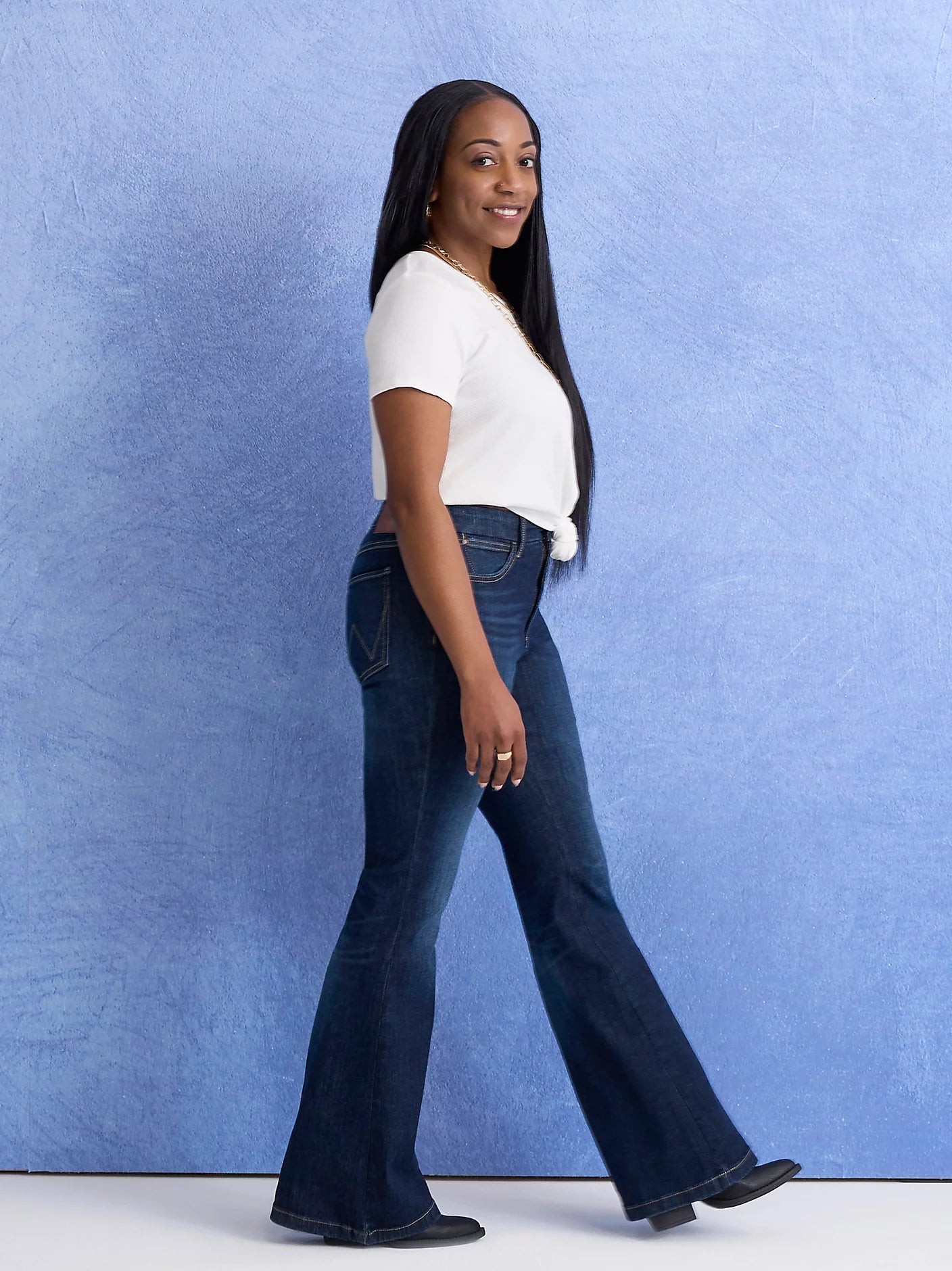 Woman in white top and jeans walking.