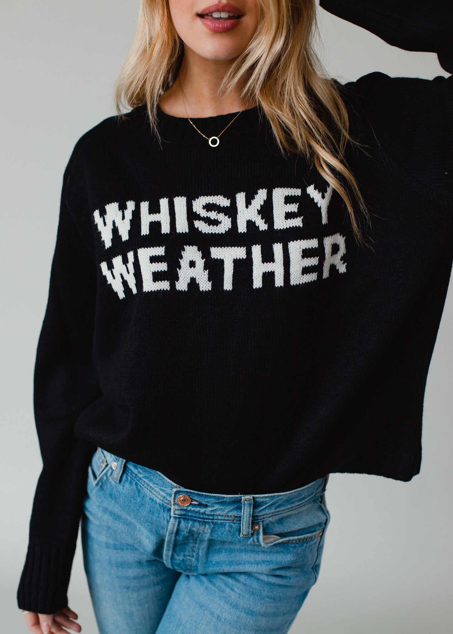 Woman wearing a black sweater that says Whiskey Weather.