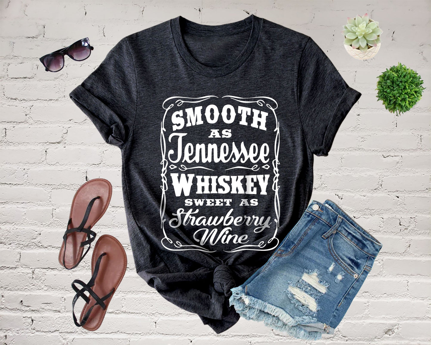 Black t-shirt with text, sunglasses, sandals, shorts, and plants.