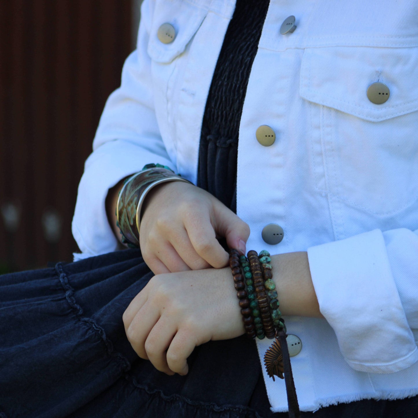 Woman's hands wearing bracelets, white jacket, and black dress.