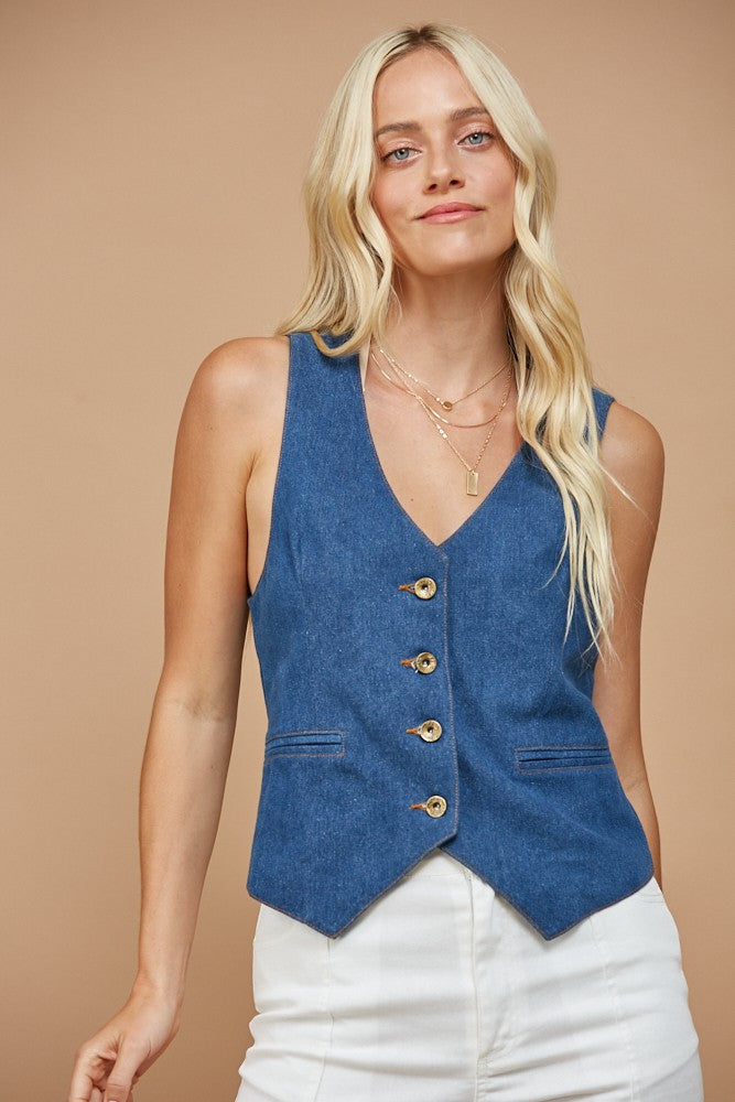 Woman wearing a blue denim vest and white pants.