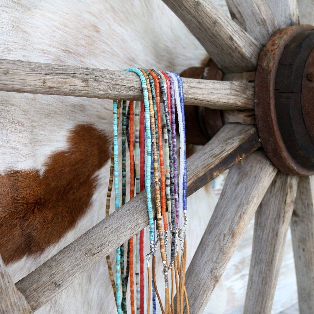 Beaded necklaces hanging on a wooden wagon wheel.