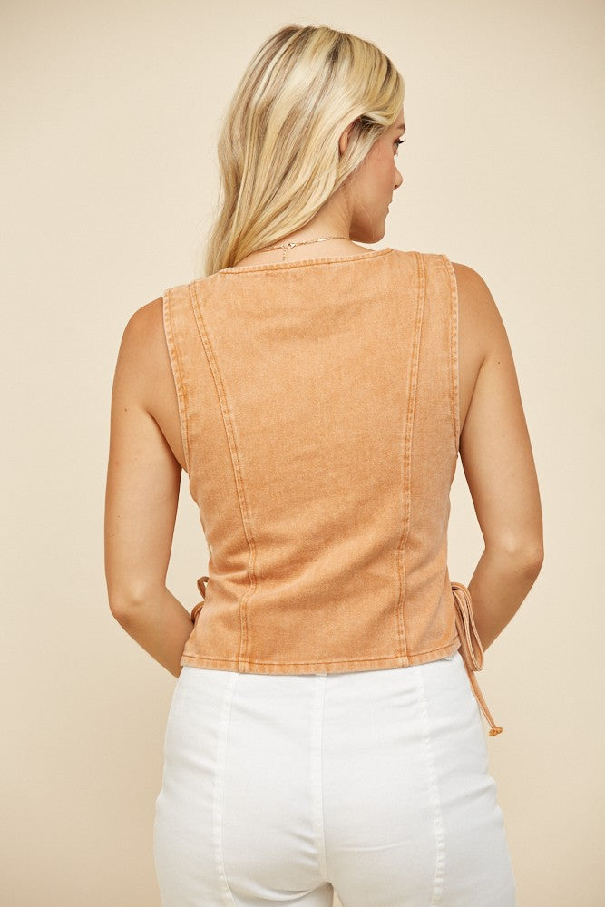 Woman wearing a tan sleeveless top.