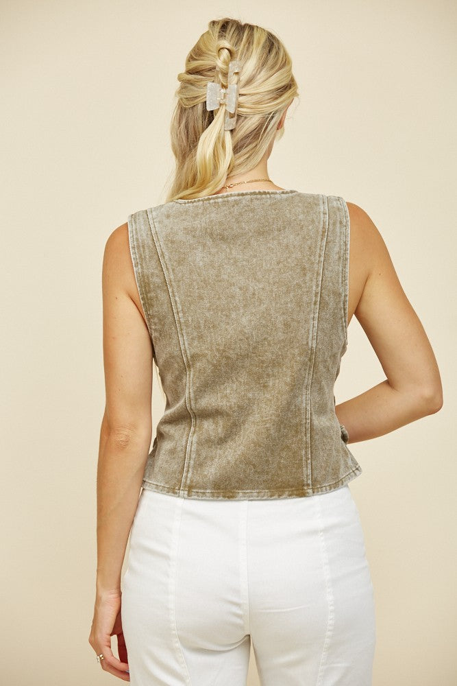 Woman wearing a green vest and white pants.