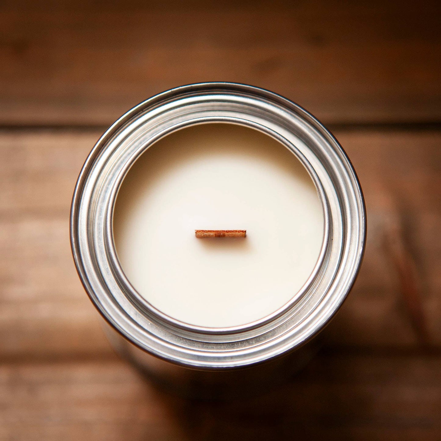 Candle in a silver tin with wooden wick.