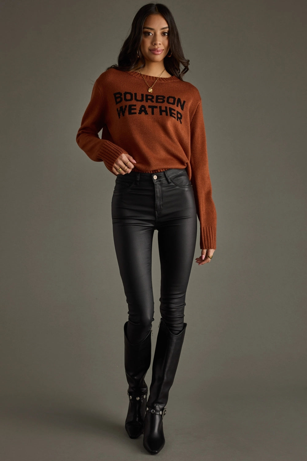 Woman wearing brown sweater and black pants.