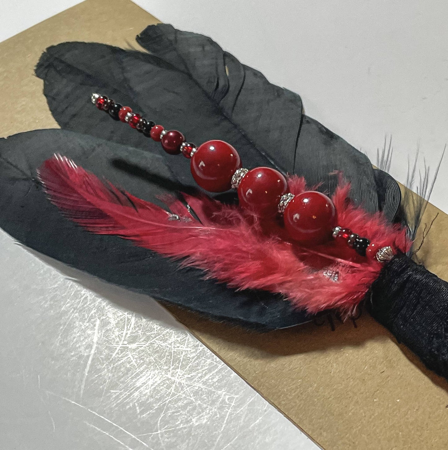 Black feather with red and black beads and red feather.