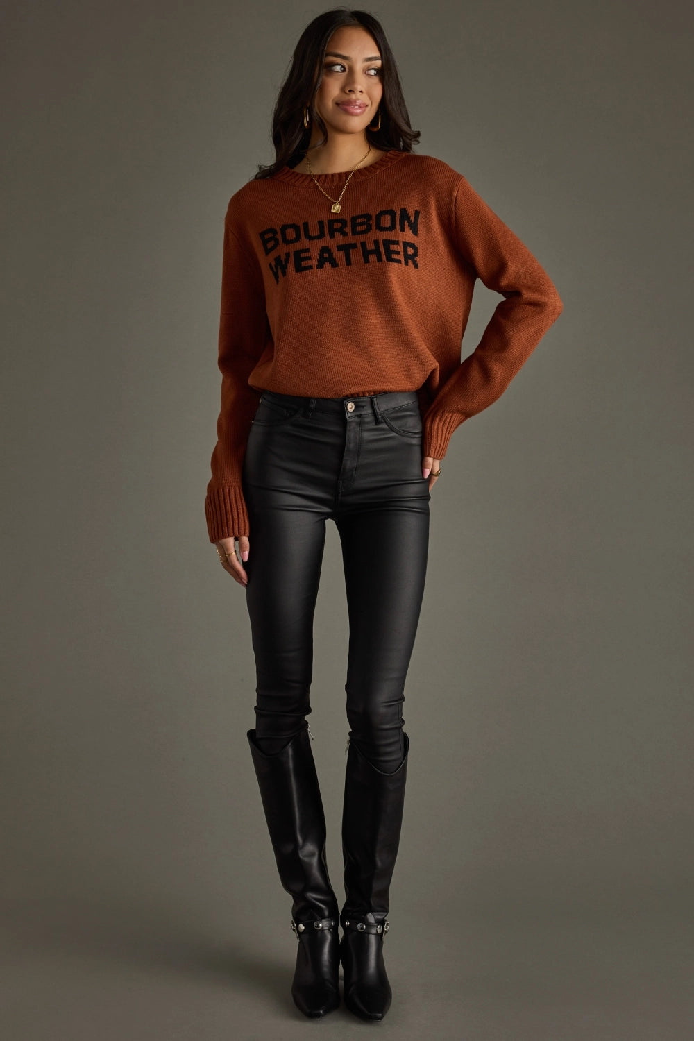 Woman in sweater, black pants, and boots.