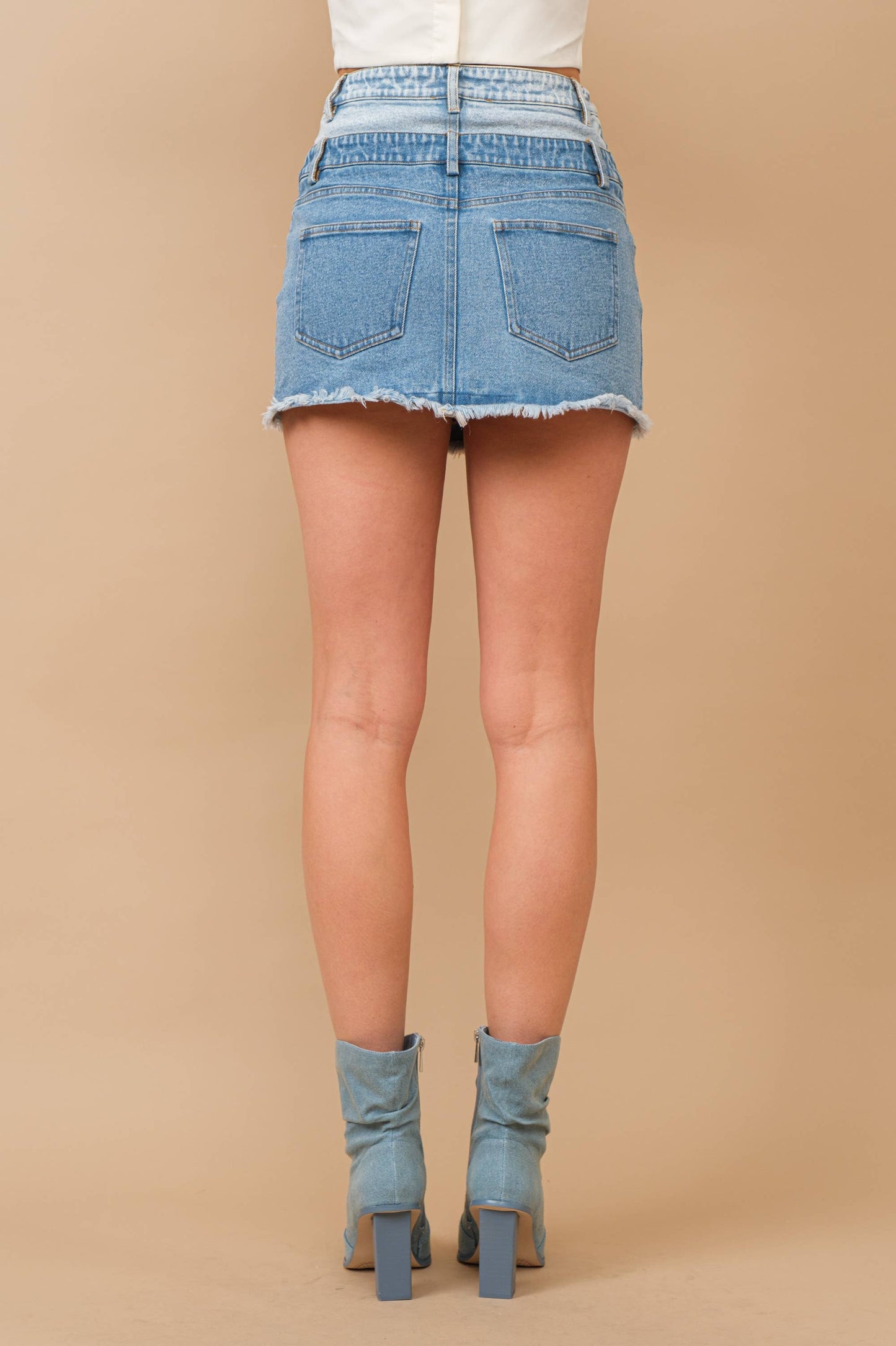 Woman wearing denim skirt and boots.
