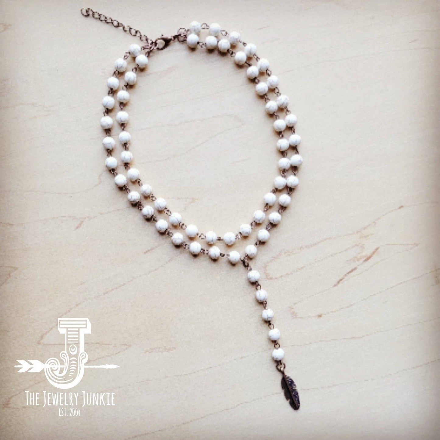 White beaded necklace with feather charm.