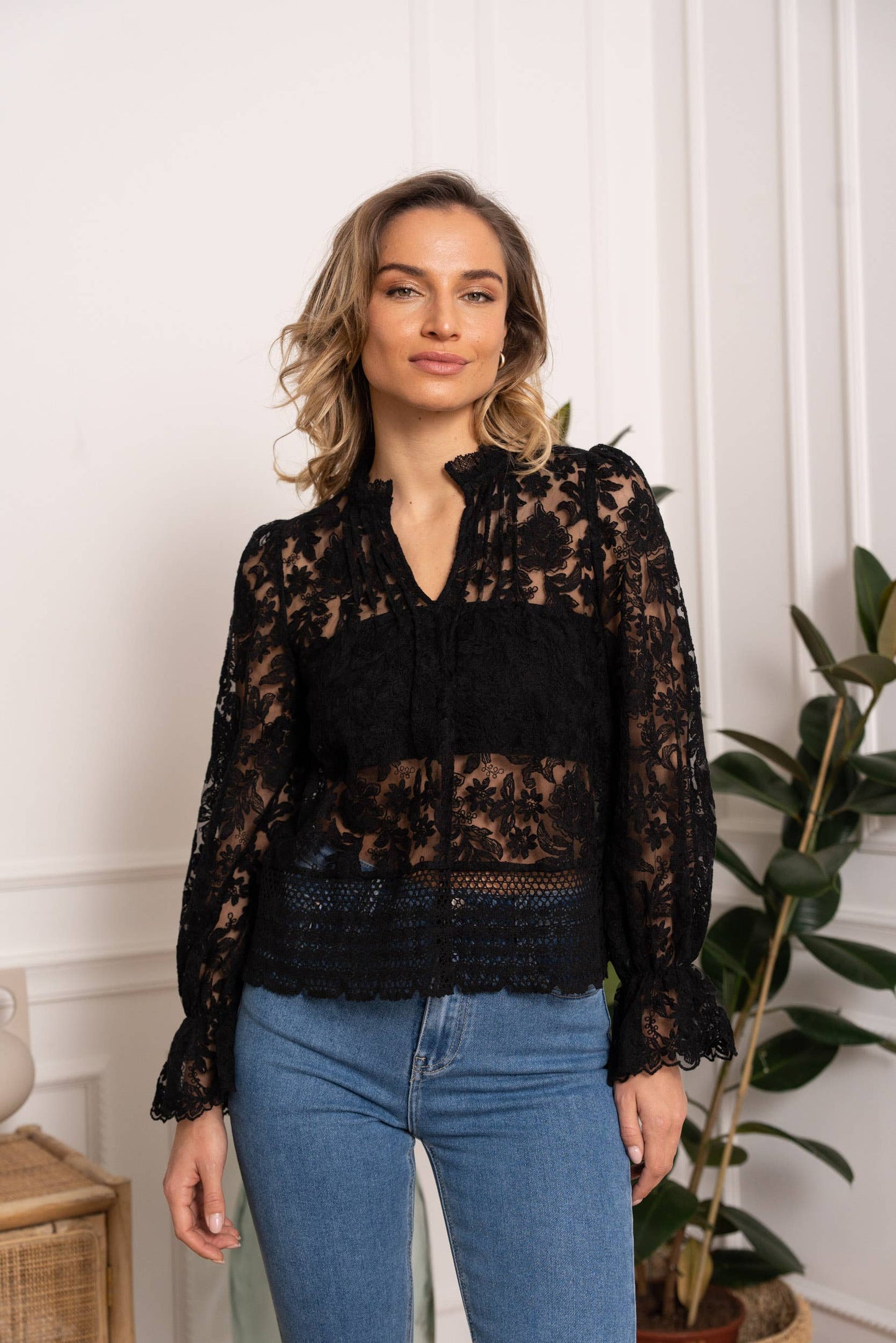 Woman wearing a black lace top and jeans.