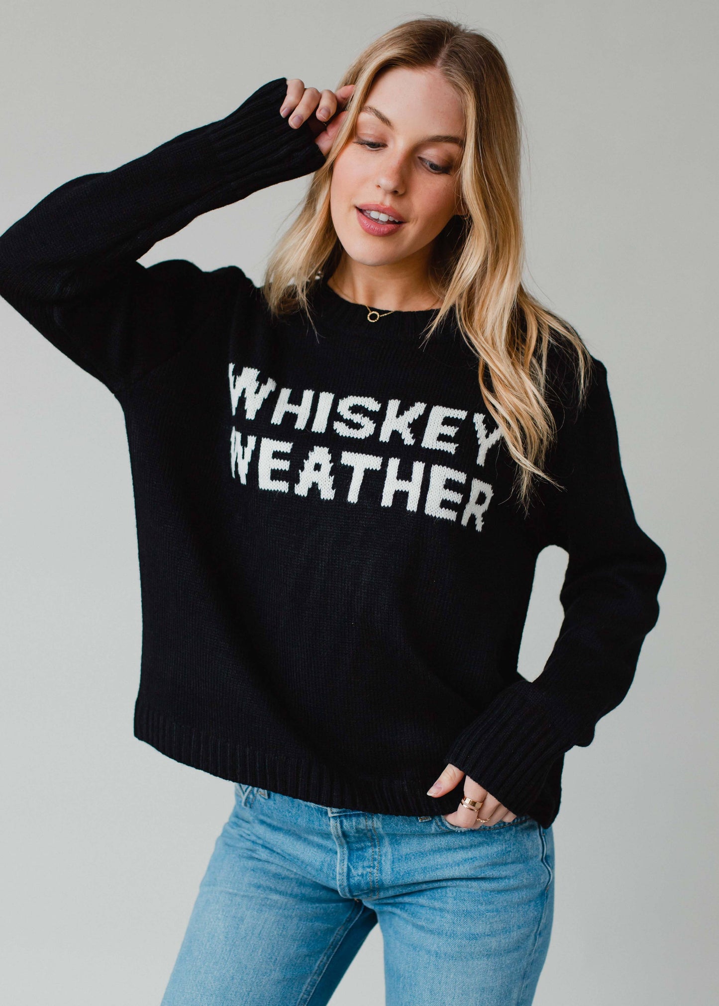 Woman wearing black sweater with WHISKEY WEATHER text.