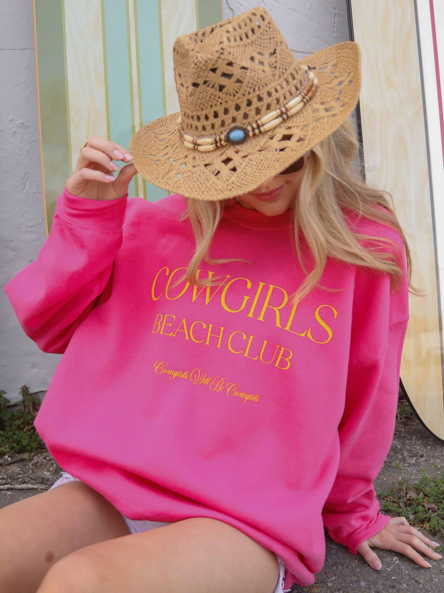 Woman in pink sweatshirt and straw hat.