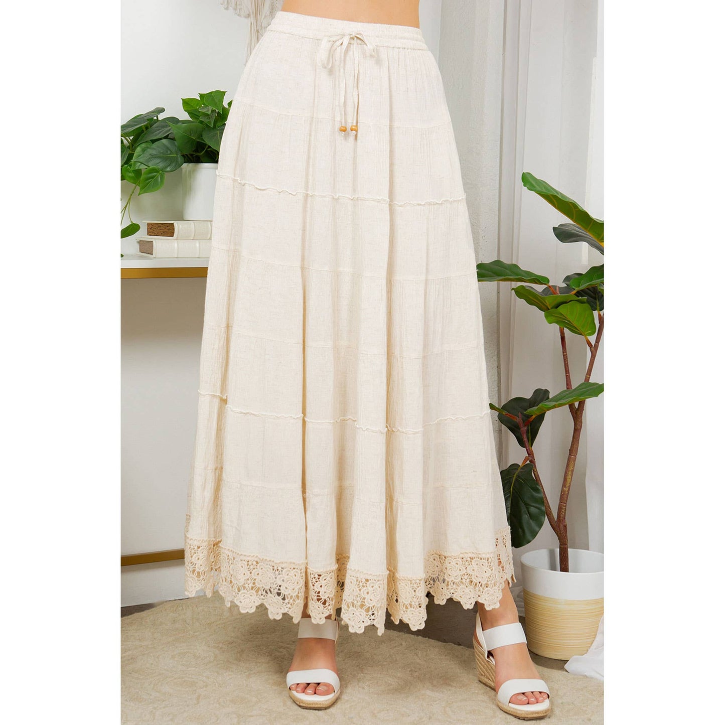 Woman wearing a long, cream-colored skirt with sandals.