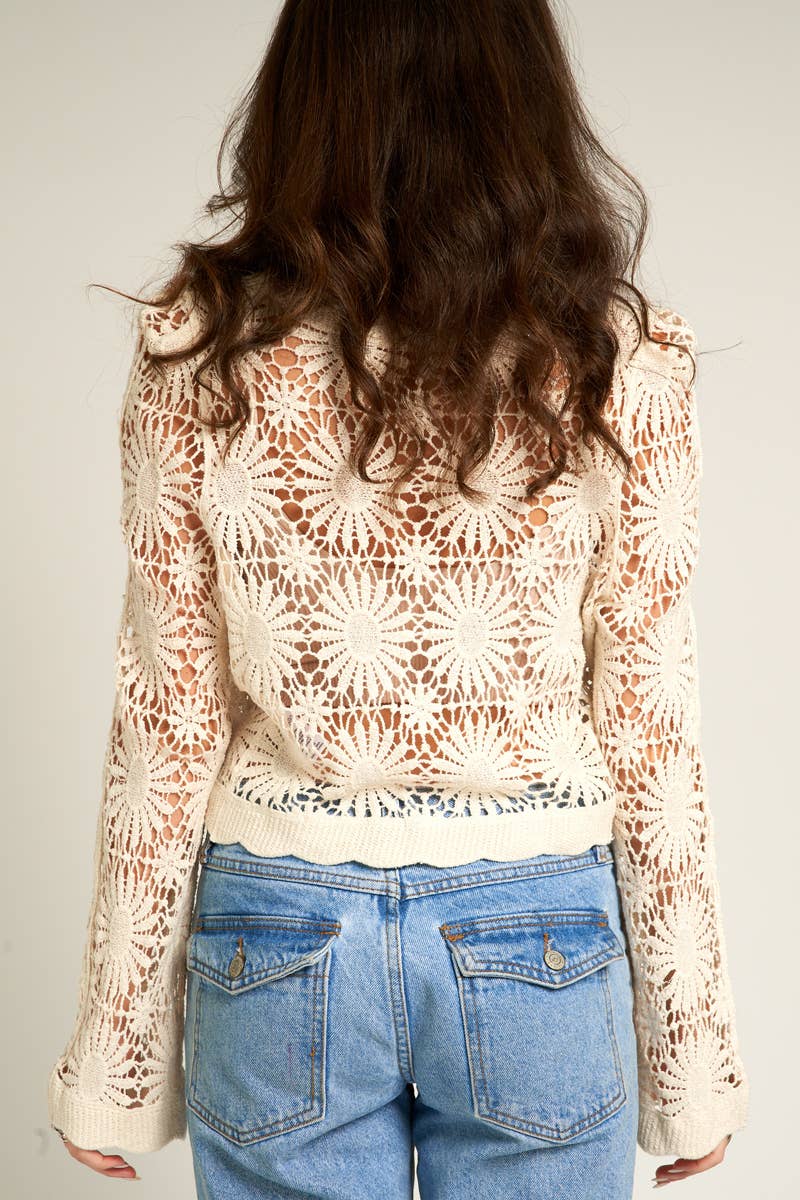 Woman wearing a crocheted jacket and jeans.