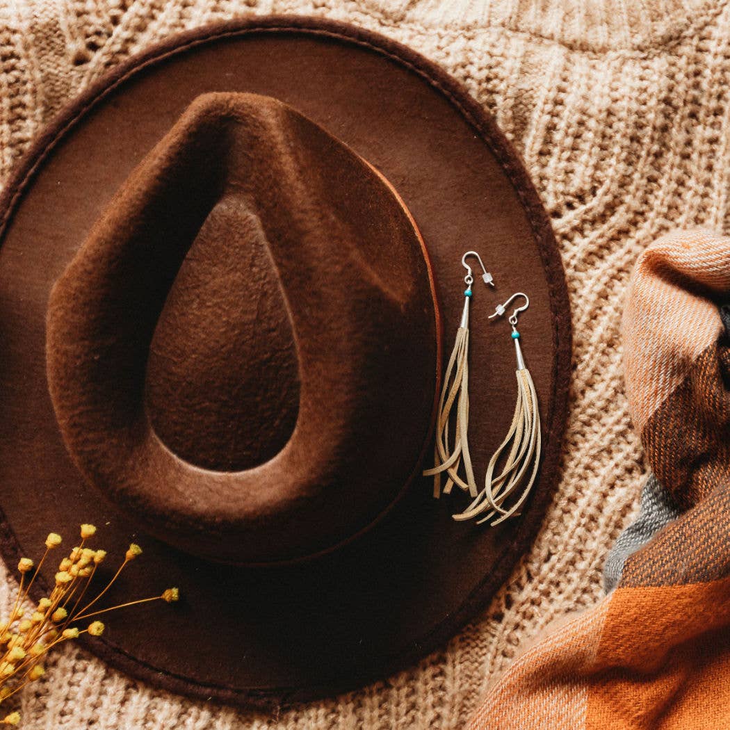 Brown hat, earrings, and scarf on a sweater.