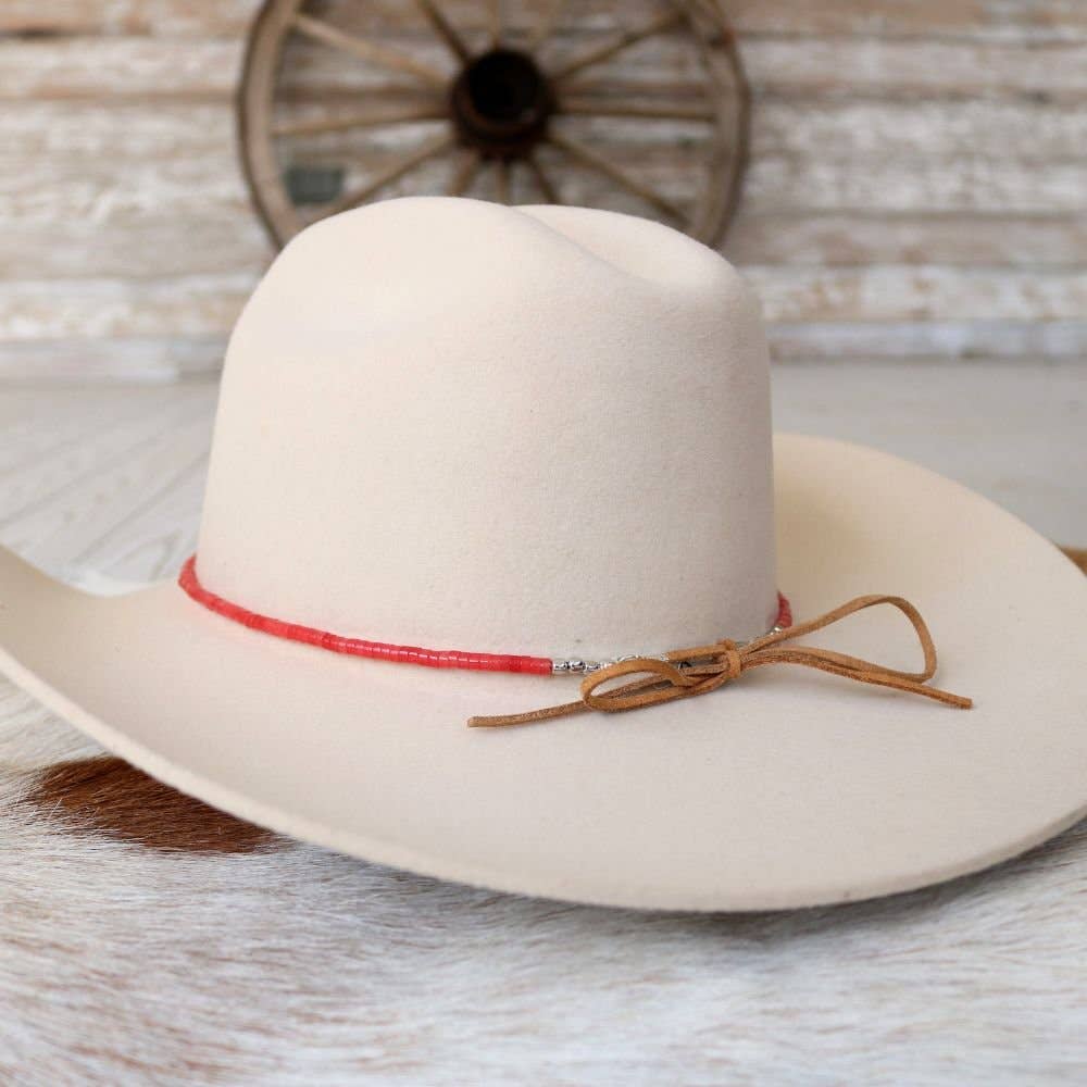Cream-colored cowboy hat with red band and leather tie.