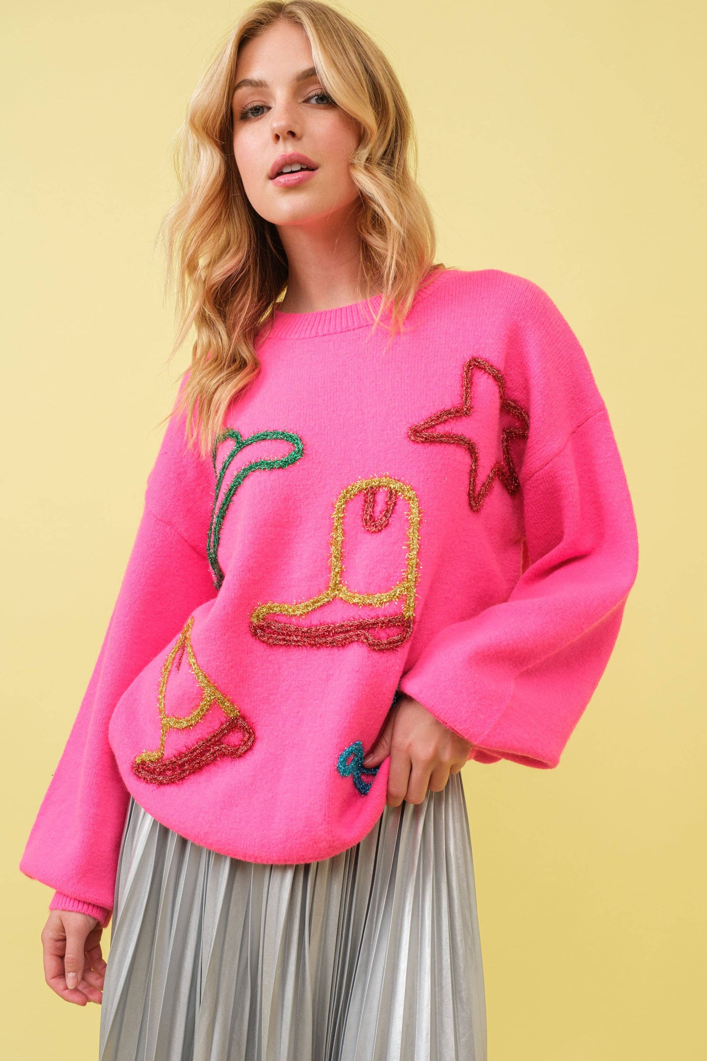 Woman wearing pink sweater with boot and star designs.