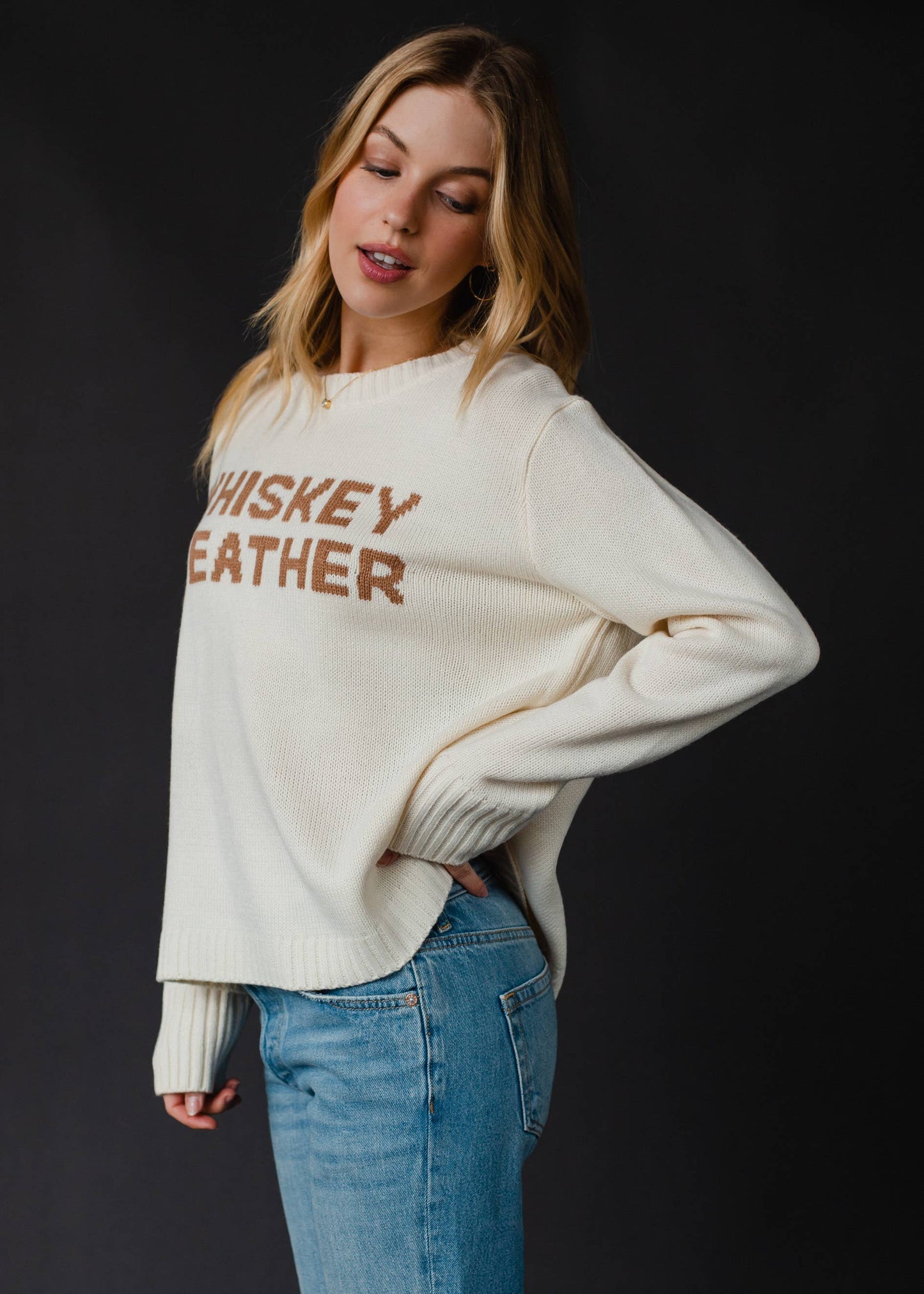 Woman wearing cream sweater with text.