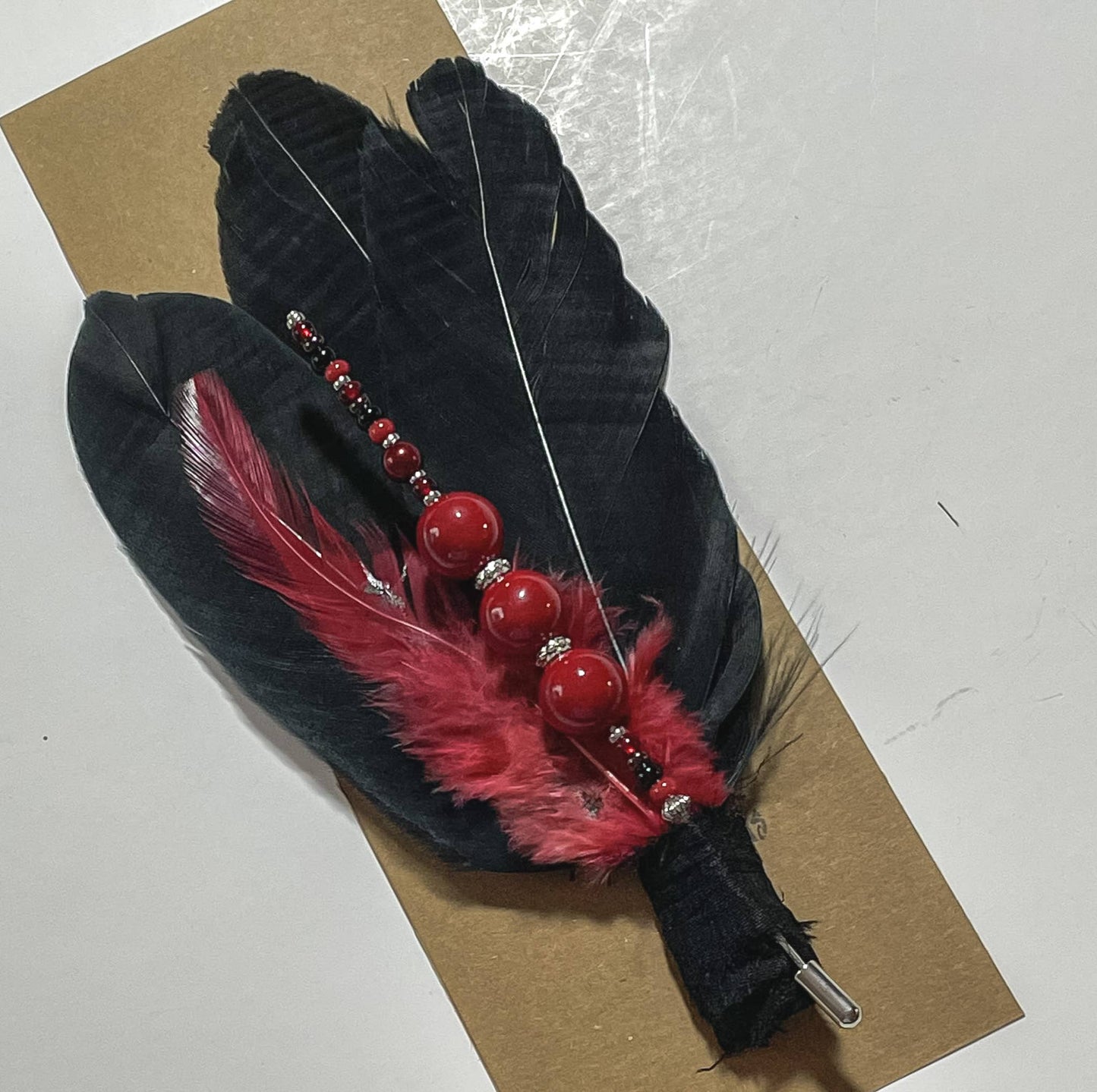 Black and red feather pin with beads.