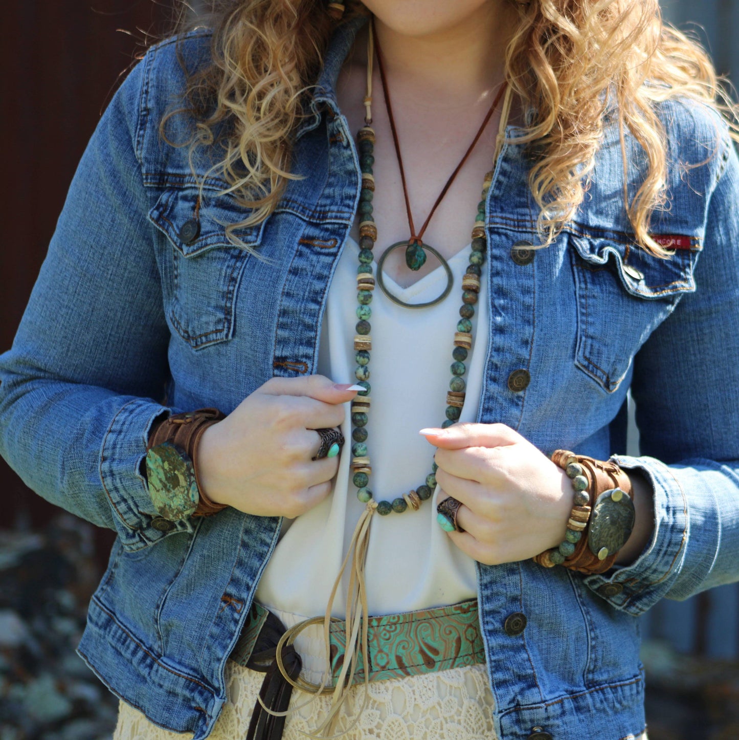 Woman in denim jacket and jewelry.
