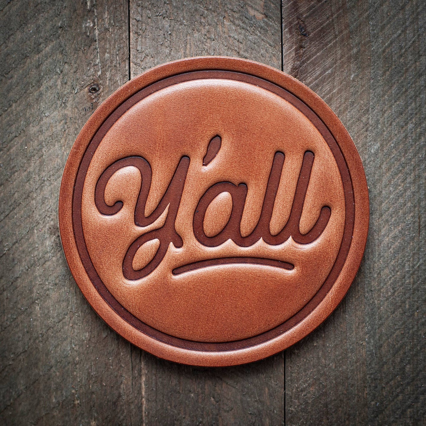 Leather coaster with the word y'all.