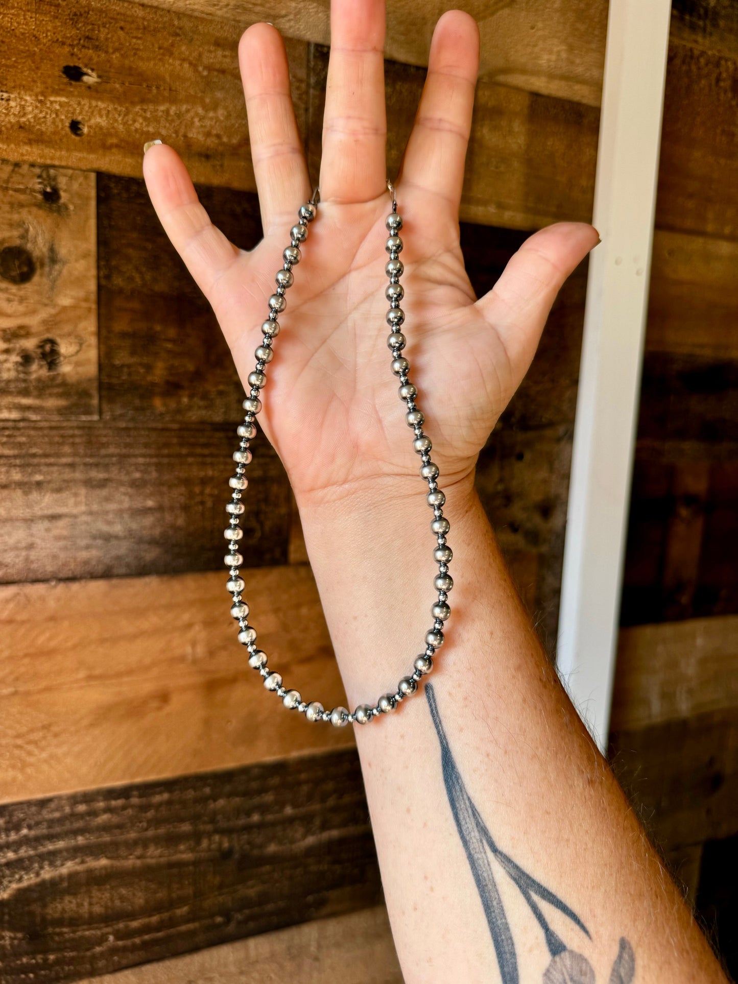 Hand holding a silver beaded necklace.