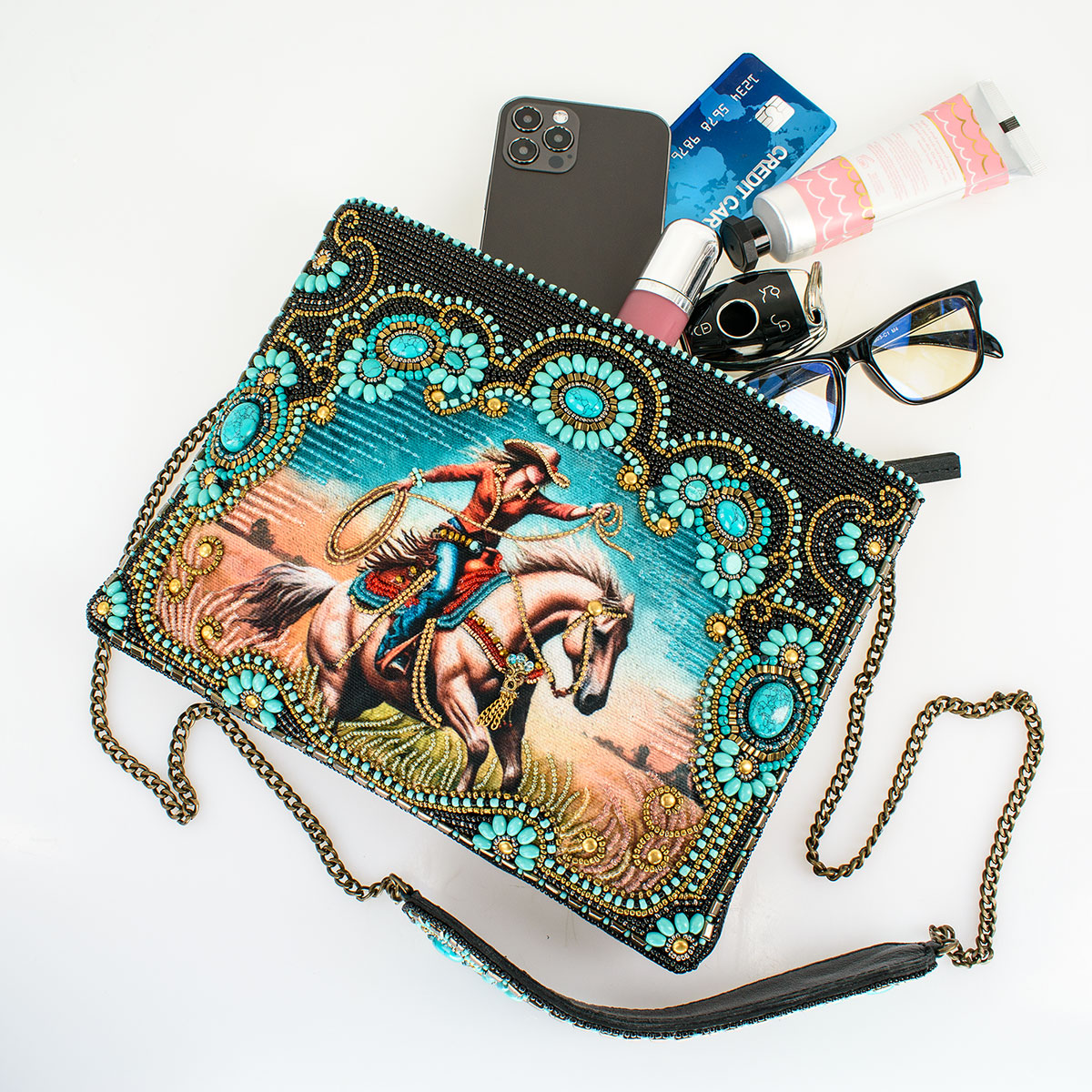 Beaded purse with cowboy graphic, spilling contents.