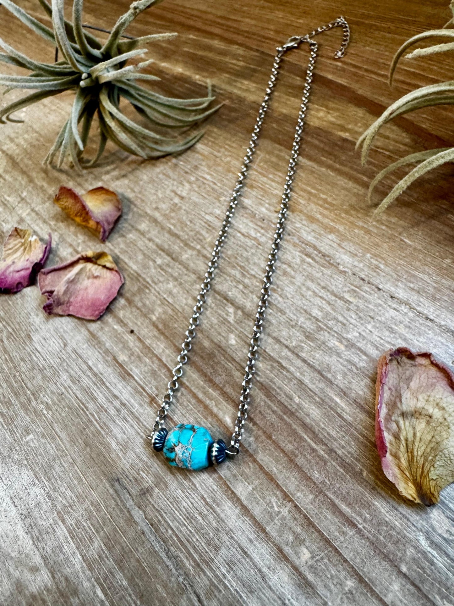 Turquoise beaded necklace with dried flowers on wood