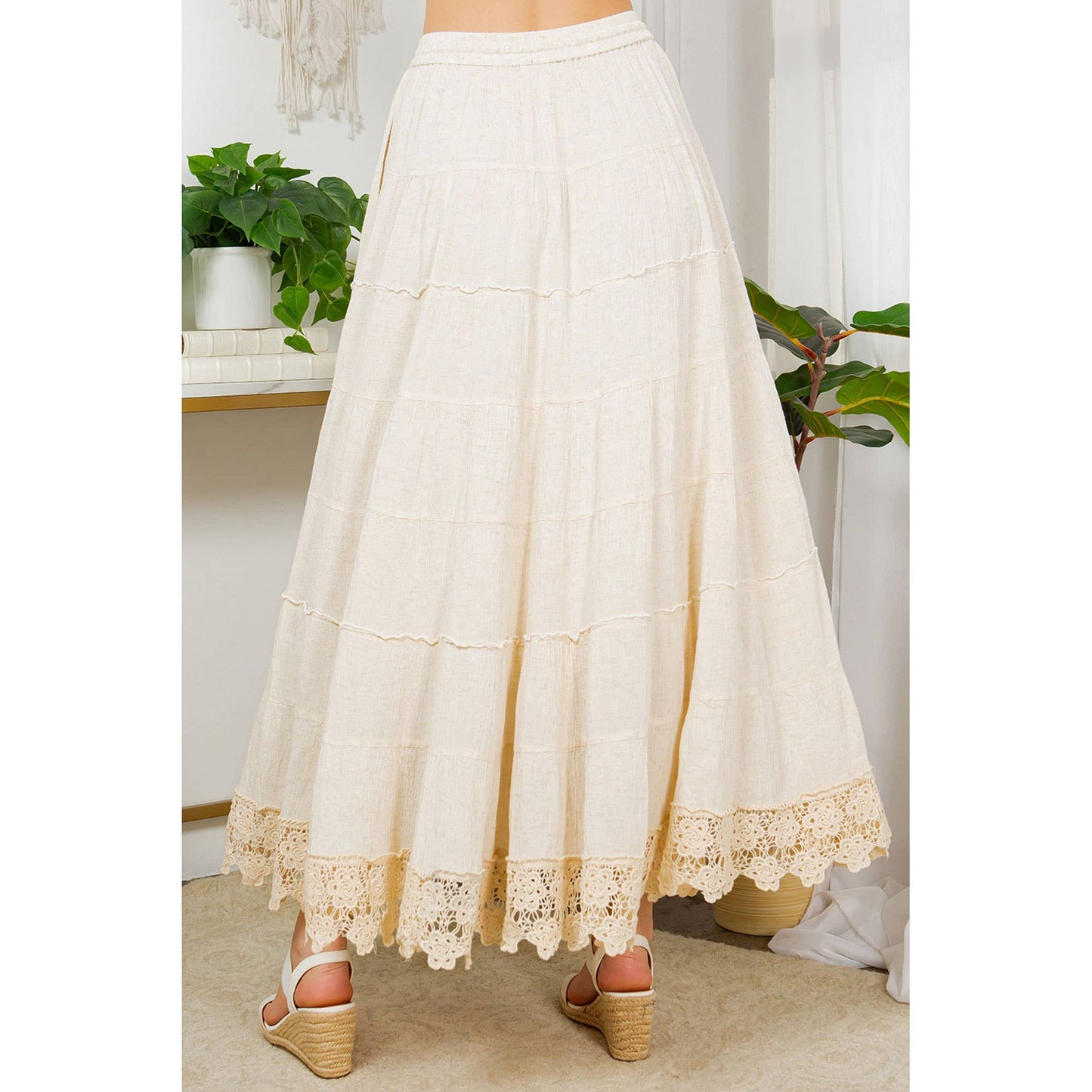 Woman wearing a long cream-colored skirt and sandals.