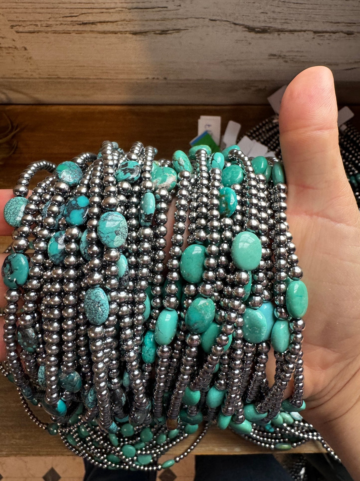 Hand holding turquoise and silver beaded bracelets.
