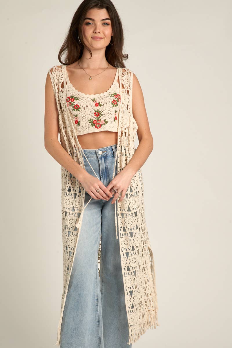 Woman in crochet vest and top, blue jeans.