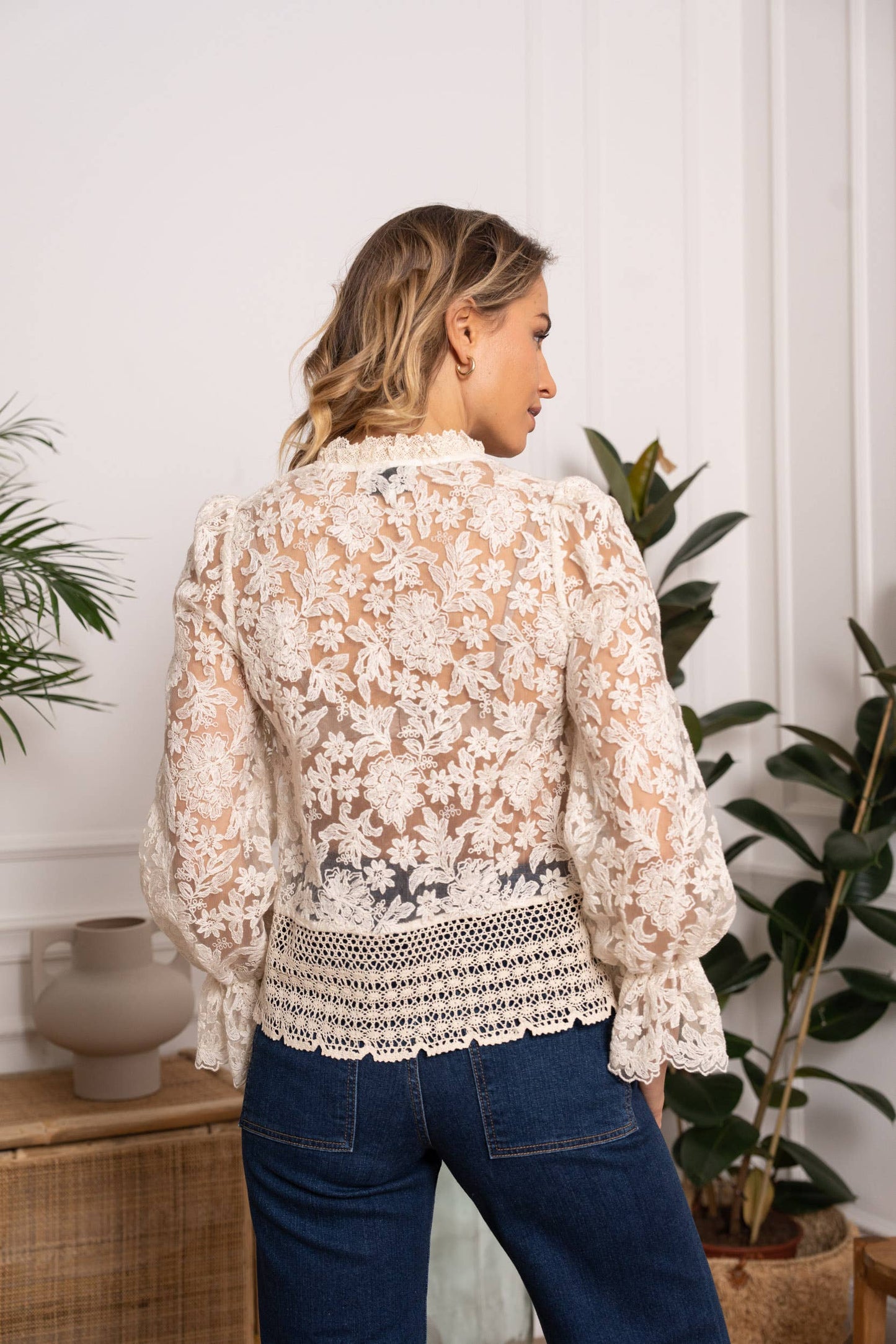Woman in a white lace top and blue jeans.
