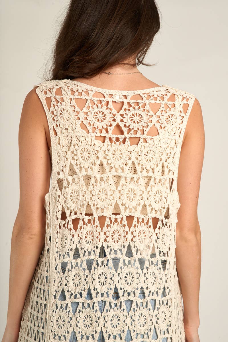Woman wearing a cream-colored crochet vest.