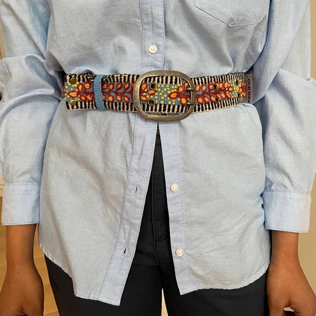 Person wearing a blue shirt and patterned belt.