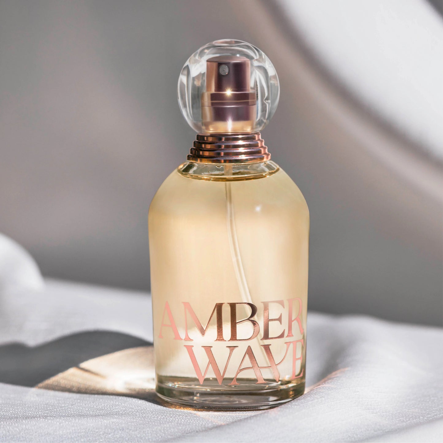 Amber Wave perfume bottle on white fabric