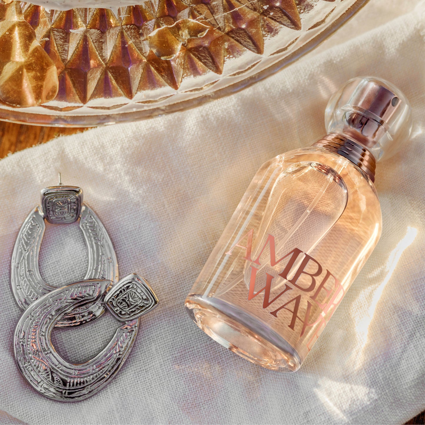 Amber Waves perfume bottle and jewelry on white cloth