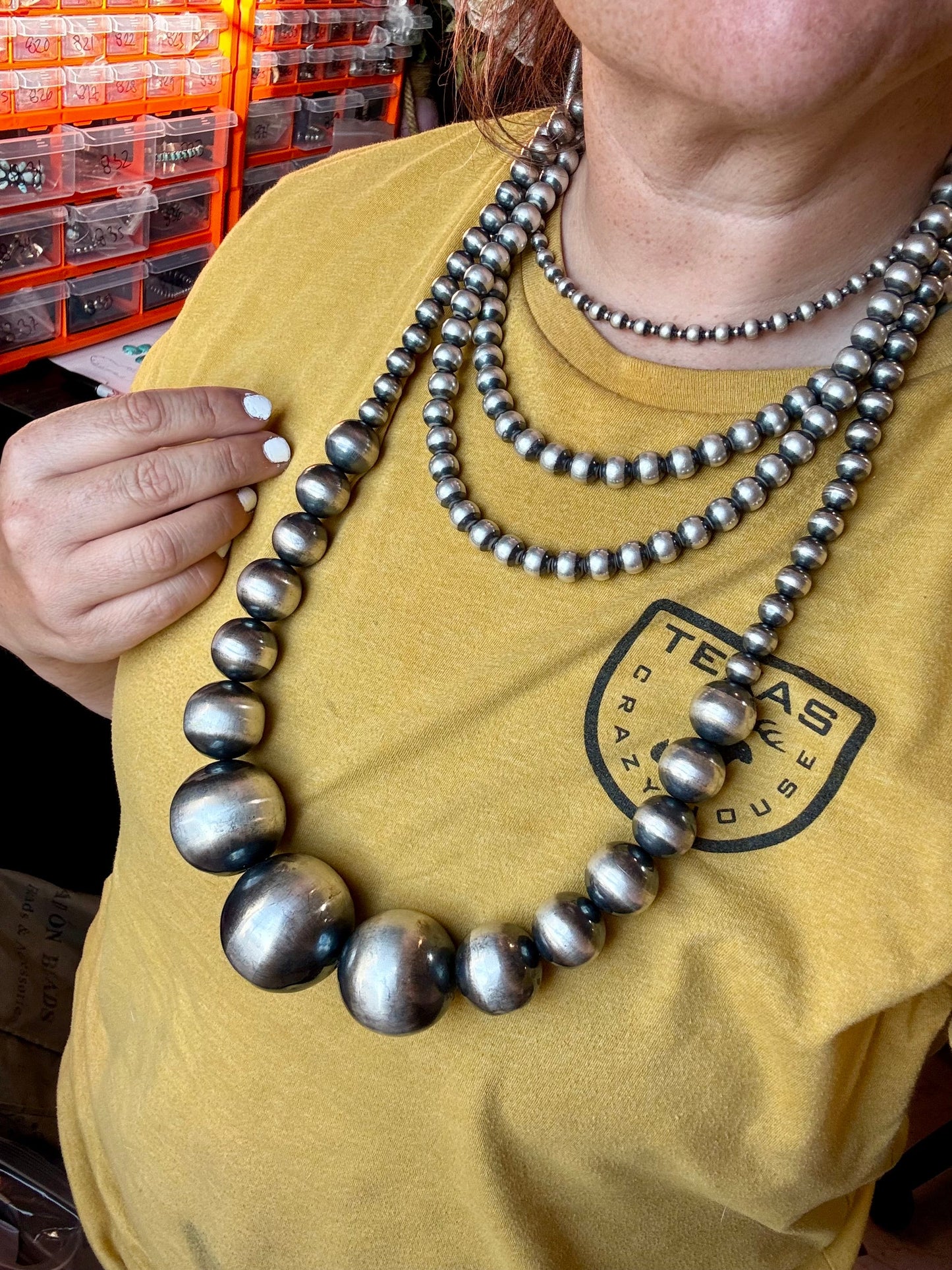 Woman wearing multiple silver bead necklaces.